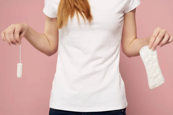 Woman with a pad in her hand on a pink background jeans T-shirt tampons hygiene frequency — Stock Photo, Image