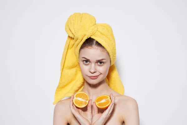 Mulher alegre com uma toalha amarela na cabeça desnudada ombros laranjas em mãos saúde pele limpa — Fotografia de Stock