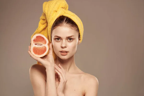 Bella donna con asciugamano sulla testa pelle pulita spalle scoperte agrumi nelle mani — Foto Stock