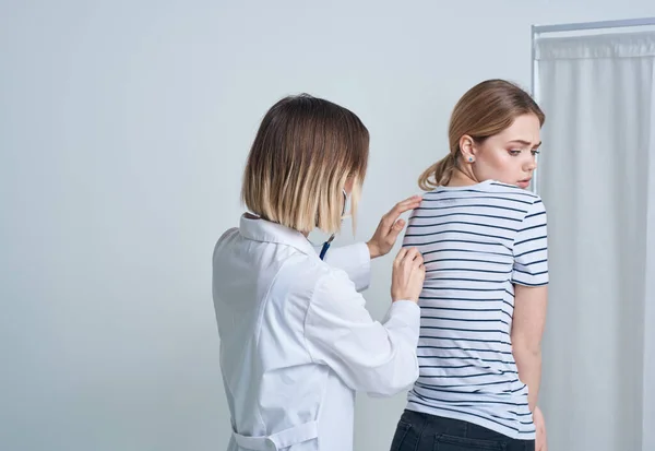 doctor woman in medical gown with stethoscope listens to patients heart