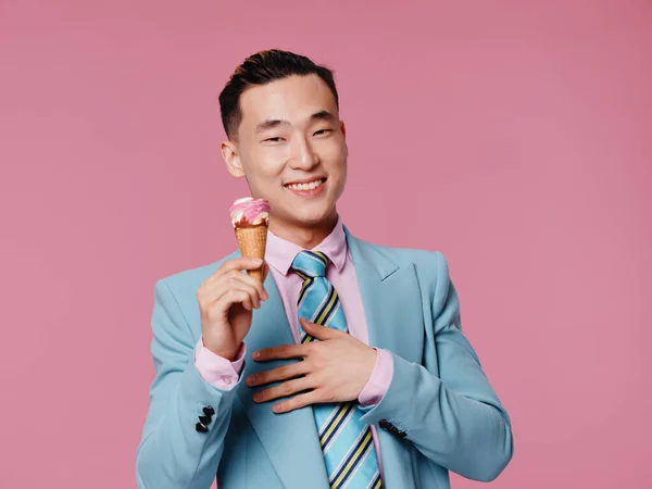 Cheerful man of asian appearance holding ice cream blue suit joy pink background — Stock Photo, Image