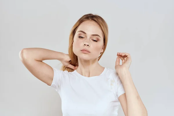 Allegra bionda in una t-shirt bianca gesticolando con le mani sfondo chiaro — Foto Stock