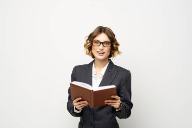 Not defteri ve gözlüklü bir iş kadını takım elbise modelinin hafif arka planında çalışıyor..