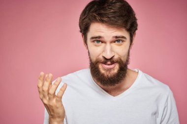 Beyaz tişörtlü adam elleriyle jest yapıyor. Duyguları var. Pembe arka plan eğlenceli.