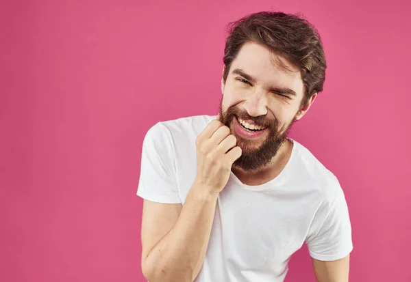 수염을 가진 쾌활 한 남자가 핑크 색 배경과 손으로 제스 쳐를 하며 웃는다 — 스톡 사진