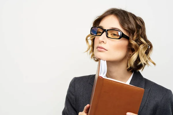 Femme d'affaires avec bloc-notes et lunettes de travail lumière arrière-plan recadré vue du modèle de costume. — Photo