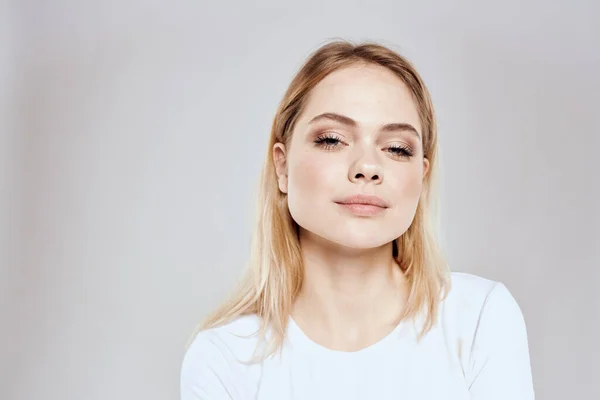 Mulher loira alegre em branco t-shirt recortada vista luz fundo — Fotografia de Stock