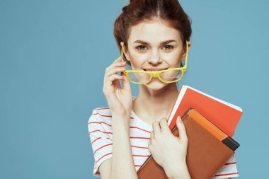Mavi arka plan ve sarı gözlük modeli saç kesimi üzerine kitapları olan bir kız öğrenci.
