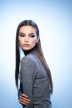 Çekici, parlak makyajlı bir kadın zarif bir modelle saçlarını düzleştiriyor.