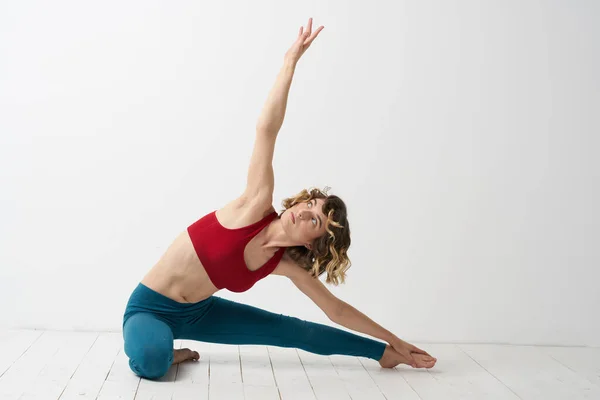 Flickan är engagerad i yoga på en ljus bakgrund Röd T-shirt gestikulera med händerna — Stockfoto