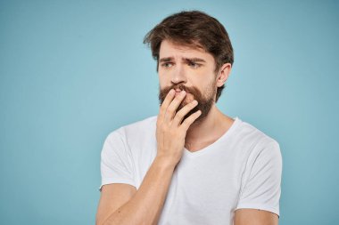 Sakallı adam duyguları beyaz tişört yaşam tarzı jestleri ve mavi arka planlar.