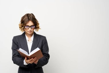 Klasik takım elbiseli bir iş kadını elinde bir not defteri ve yüzünde gözlüklerle.