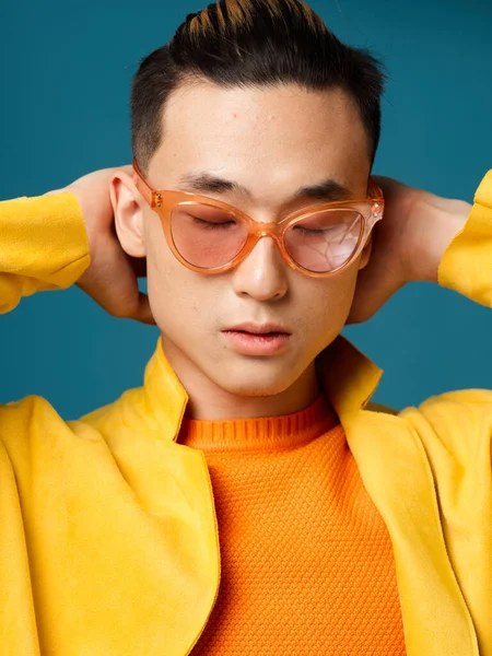 Un hombre asiático con gafas naranjas sostiene sus manos detrás de su cabeza —  Fotos de Stock