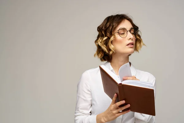 Zakelijke vrouw met notitieblok en bril op een lichte achtergrond kapsel succes emoties — Stockfoto