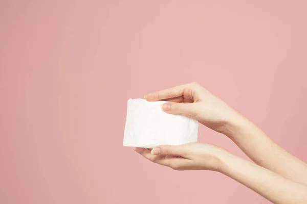 Colocação em embalagem em mãos femininas em um fundo rosa corte vista higiene aparência limpa — Fotografia de Stock