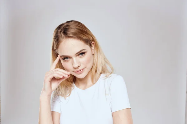 Allegro donna bionda in bianco t-shirt ritagliato vista luce sfondo — Foto Stock