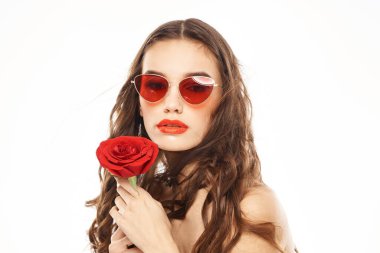 Kırmızı gül ve güneş gözlüklü, çıplak omuzlu esmer kız.