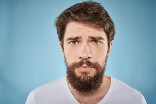 Homem barbudo desagradado expressão facial emoções close-up azul fundo branco t-shirt — Fotografia de Stock