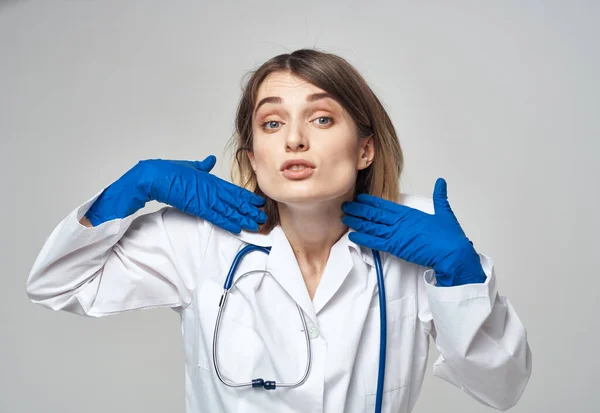 Donna emotiva in guanti medici blu tocca la testa con le mani — Foto Stock