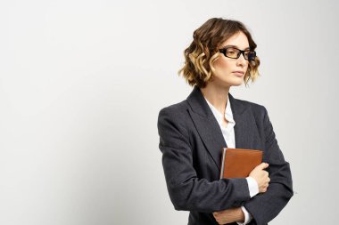 Klasik takım elbiseli bir iş kadını elinde bir not defteri ve yüzünde gözlüklerle.