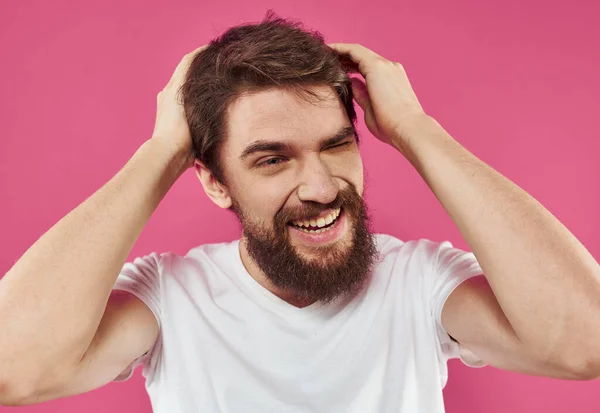 Homem entusiástico em uma camiseta branca com uma barba espessa em um fundo rosa — Fotografia de Stock