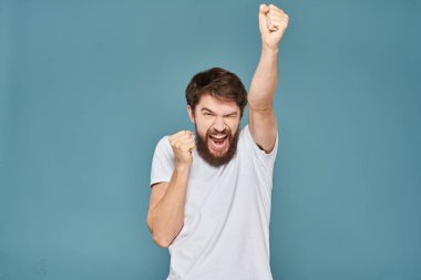 Beyaz tişörtlü, el kol hareketleri yapan, stüdyosu kesilmiş biri.