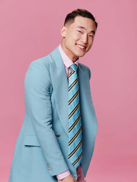 男アジアの感情笑顔青いスーツクロップドビューピンクの背景 — ストック写真