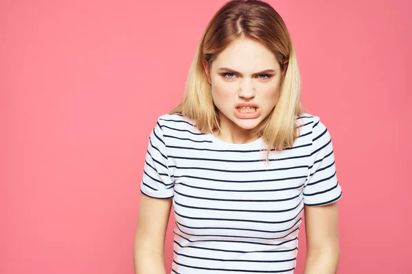 Blond randig t-shirt känslor gest händer missnöjd ansiktsuttryck rosa bakgrund — Stockfoto