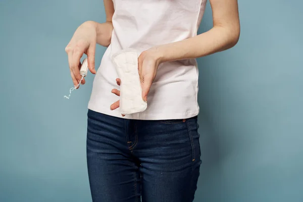 Menina com um tampão e uma almofada em suas mãos em um fundo azul higiene limpeza menstruação — Fotografia de Stock