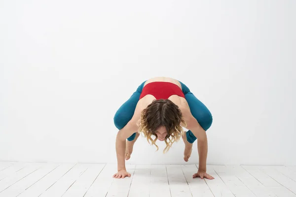 Wanita melakukan yoga full length indoors blue leggings red tank top — Stok Foto