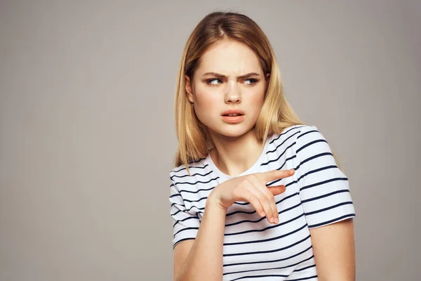 Μια γυναίκα με μια δυσαρεστημένη έκφραση είναι gesturing με τα χέρια της T-shirt γκρι φόντο — Φωτογραφία Αρχείου