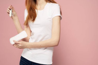 Elinde ped olan bir kadın pembe arka plan kotlu tişört ped hijyen sıklığı