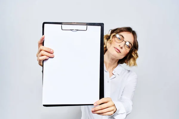 Деловая женщина с папкой с белыми документами в руке на светлом фоне и моделью очков в стиле прически — стоковое фото