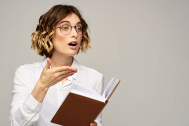 Elinde not defteri olan kadın iş hayatında bej arka plan gözlüklü saç stili.