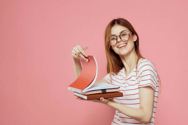 Mladá studentka s knihami na růžovém pozadí brýle na tváři vzdělávání ústav oříznutý pohled — Stock fotografie