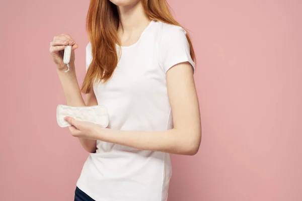 Vrouw met een kussen in haar hand op een roze achtergrond jeans T-shirt tampons hygiëne frequentie — Stockfoto