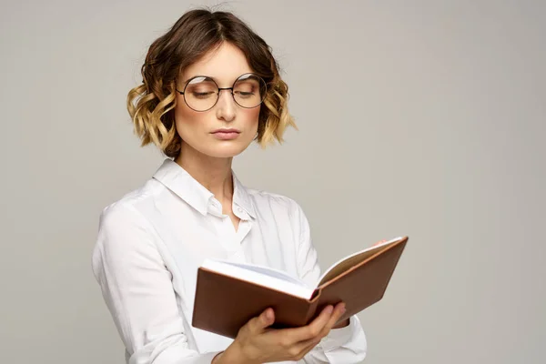 Vrouw met notitieblok in handen zakelijke werk beige achtergrond bril kapsel — Stockfoto