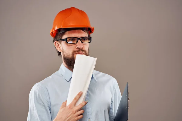Человек в строительной форме оранжевый шлем чертежи документов работы услуги — стоковое фото
