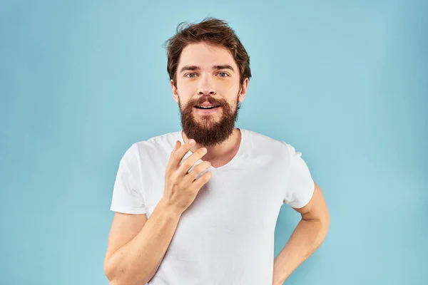 Homem emocional com uma barba em um branco t-shirt azul fundo divertido estilo de vida — Fotografia de Stock