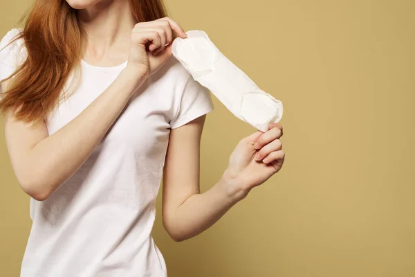 Menina com uma almofada limpa na mão em um fundo bege corte vista da menstruação dias críticos higiene — Fotografia de Stock