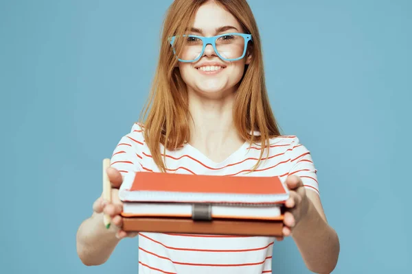 Meisje in modieuze bril met notebooks in handen op een blauwe achtergrond bijgesneden uitzicht Copy Space — Stockfoto