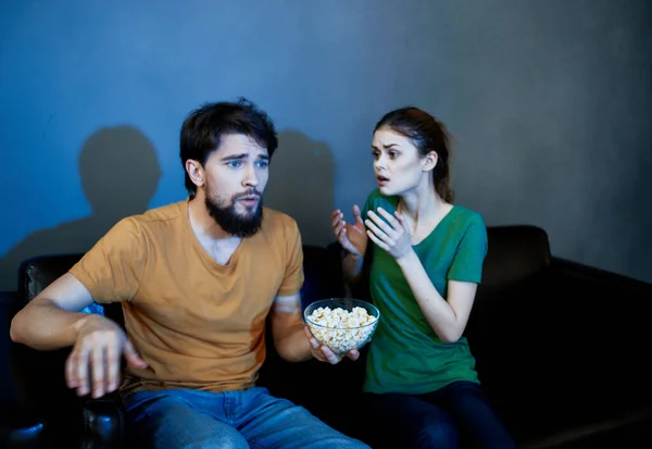 Mann und Frau abends auf Ledercouch mit Popcorn vor dem Fernseher — Stockfoto