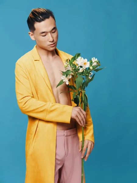 Um tipo de casaco amarelo. Aparência asiática. Buquê de flores brancas fundo azul — Fotografia de Stock