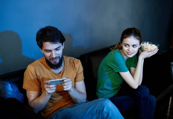 Mann und Frau abends auf Ledercouch mit Popcorn vor dem Fernseher — Stockfoto