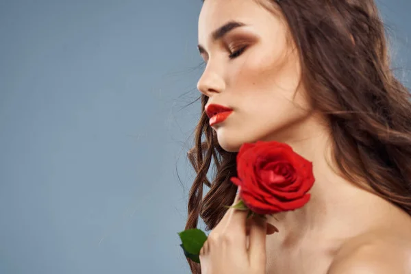 Portrait de femme avec rose rouge près du visage sur fond gris et maquillage cheveux bouclés — Photo