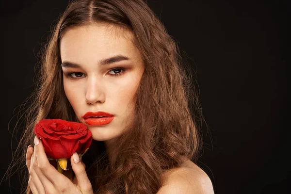 Femme avec une rose rouge sur un fond sombre cheveux longs maquillage lèvres rouges — Photo