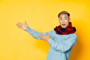 Sarı arka planda eşarbı olan adam ellerini uzayı kopyaladığını gösteriyor.