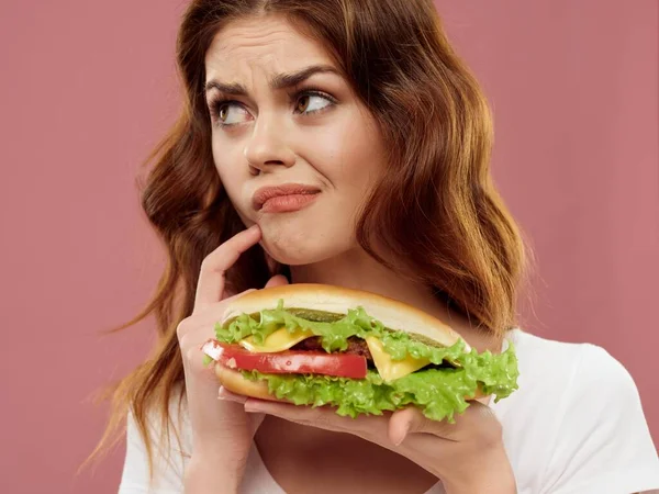Verontrustende vrouw met hamburger witte tank top op roze achtergrond look — Stockfoto