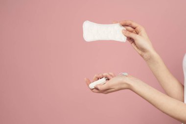 Koruyucu ped ve tampon pembe arka plan regl günlerinde kadınların elinde.