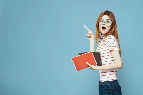 Dívka v módní brýle s notebooky v rukou na modrém pozadí oříznutý pohled kopírovat prostor — Stock fotografie